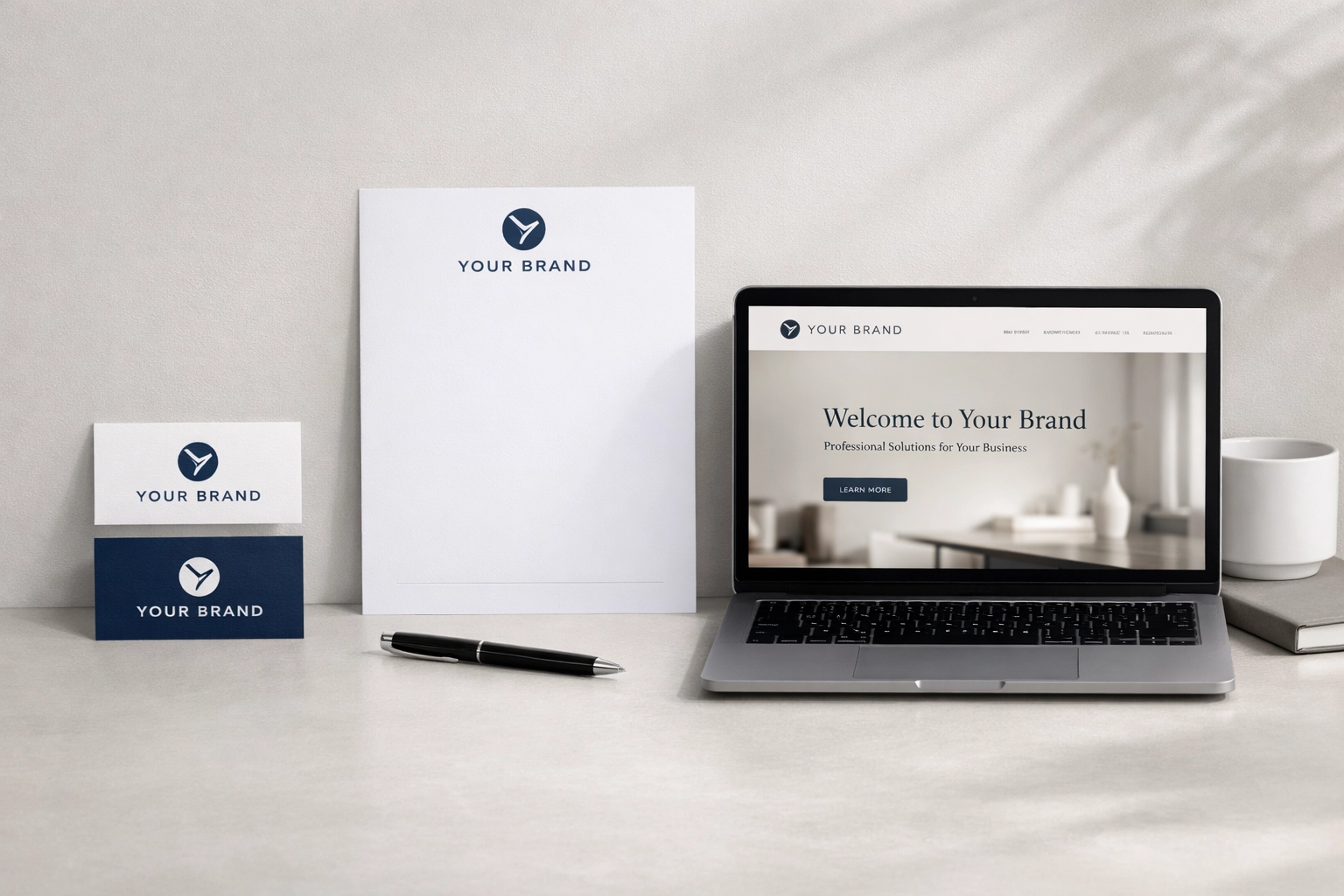 Clean, modern branding mockup with business cards, letterhead, and a laptop displaying a professional website design in a minimalist workspace.